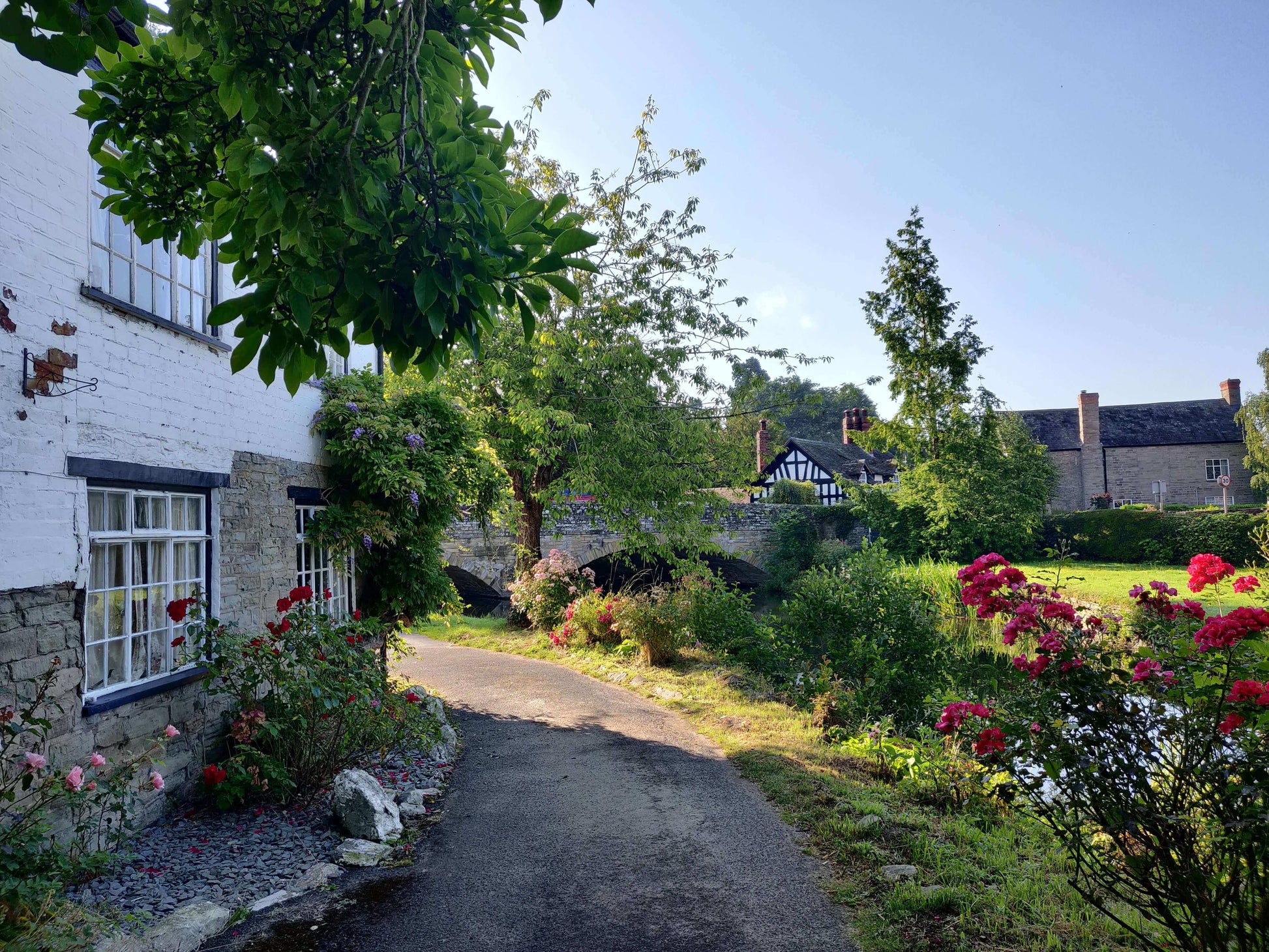 An old house surrounded by trees, a river and a stone bridge