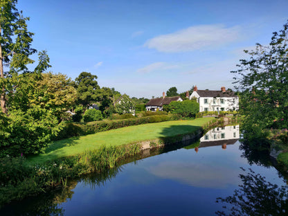 An old village surrounded by green grass, trees and with a river running through