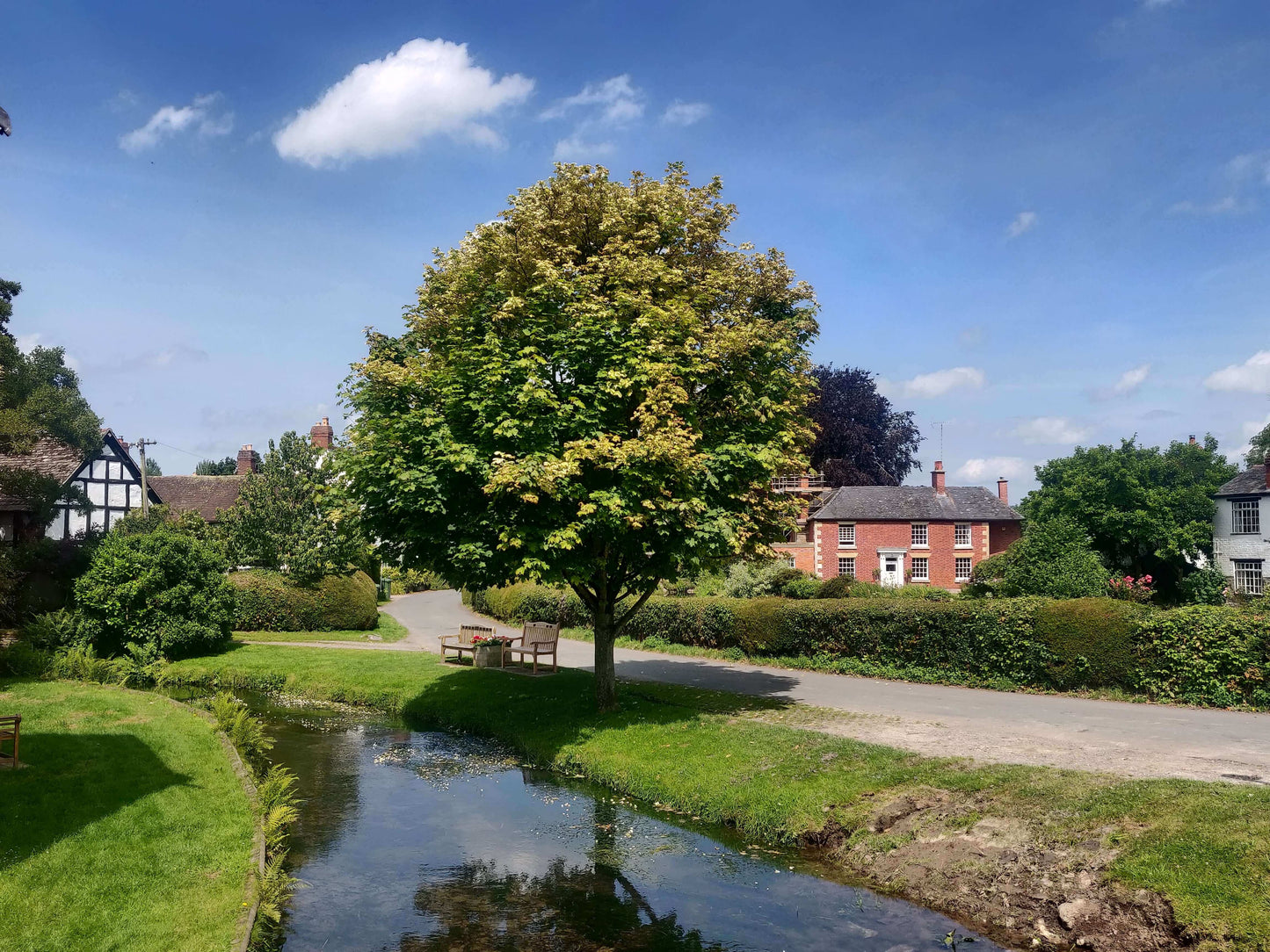 An English village with a river, trees and blue sky